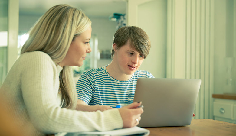 Zwei junge Leute mit Notebook und Heft beim Lernen.