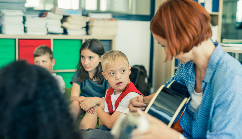 Eine Betreuerin spielt für mehrere Kinder Gitarre.