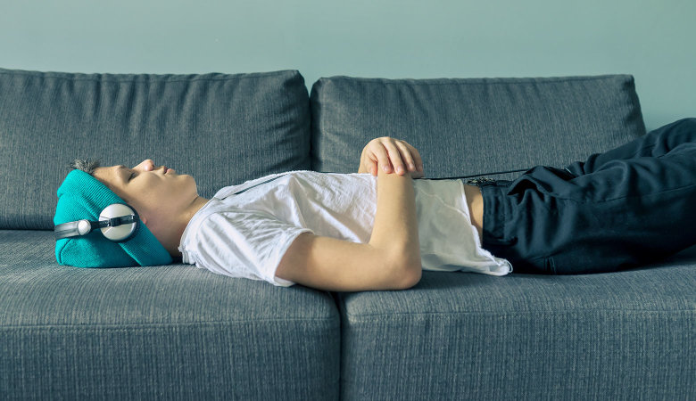 Ein Junge ohne sichtbare Behinderung liegt auf einem Sofa.