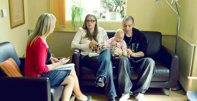 In einer Beratungsstelle: ein junges Paar mit Baby spricht mit einer Beraterin.