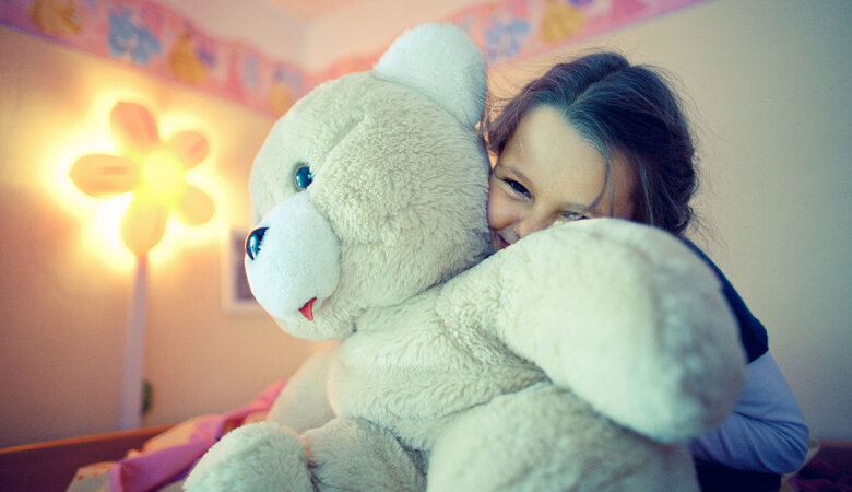 Ein Mädchen kuschelt einen großen Teddybär. 