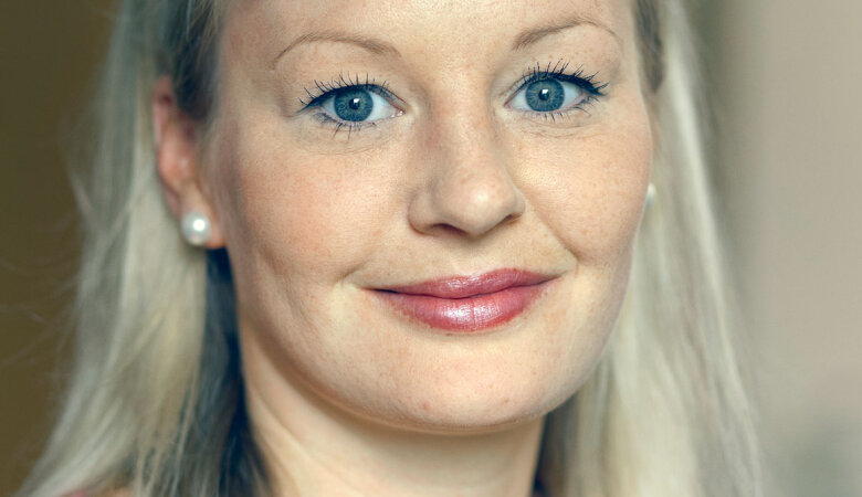 Porträtaufnahme von einer Frau mit blonden Haaren, die lächelt. 