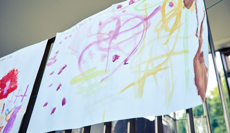 Szene im Kindergarten: Bunte Bilder hängen nebeneinander an einer Schnur.