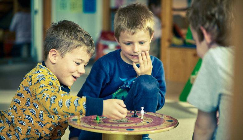 Szene im Kindergarten: Zwei Jungen spielen zusammen ein Brettspiel.