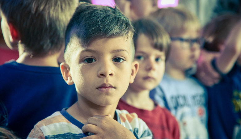 Szene im Kindergarten: Mehrere Kinder haben sich dicht an dicht aufgestellt.